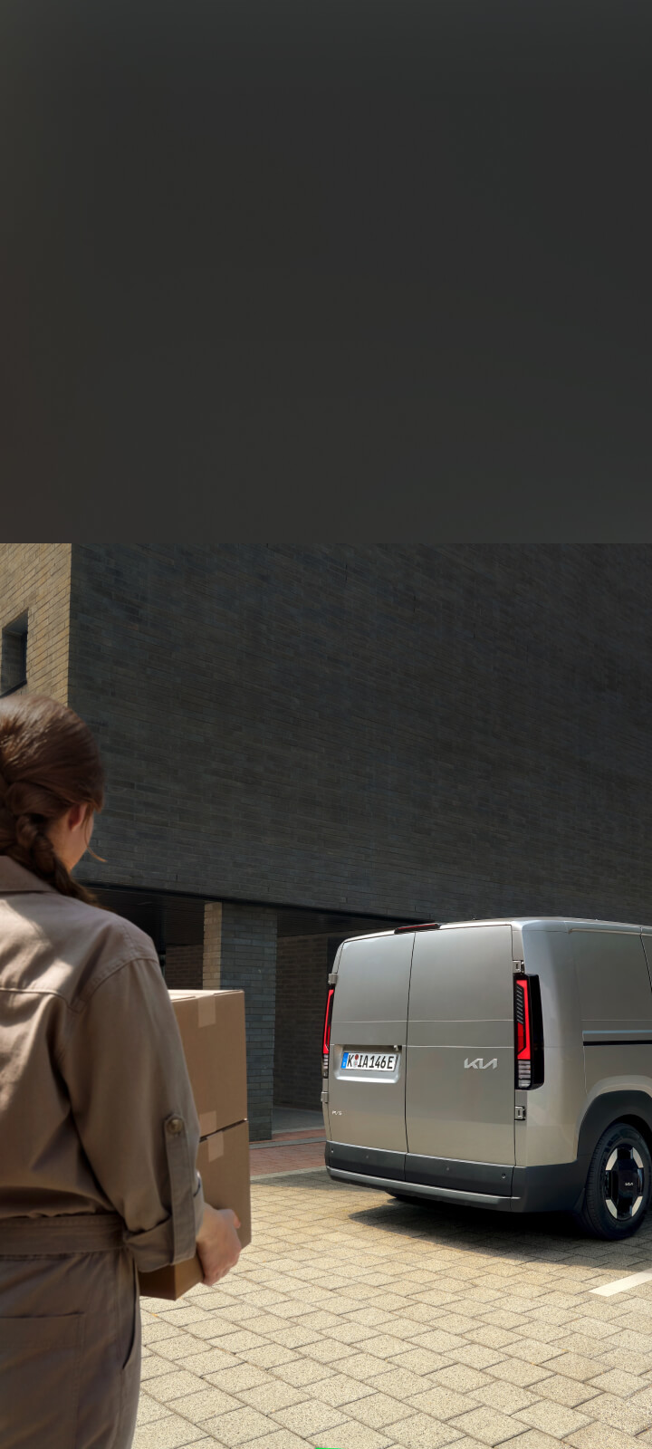 Lieferfahrer entlädt Brotkisten aus der Seitentür des Kia PV5 Cargo.
